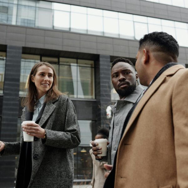 A group of diverse professionals discussing business during a coffee break outdoors.