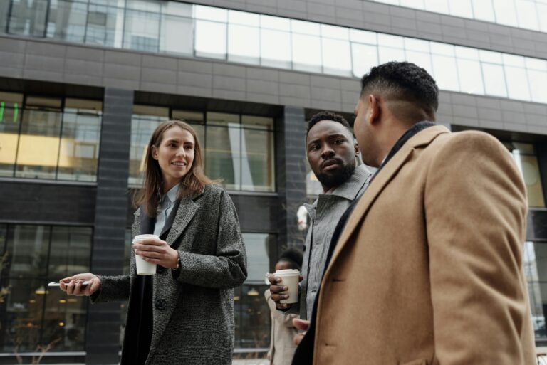 A group of diverse professionals discussing business during a coffee break outdoors.